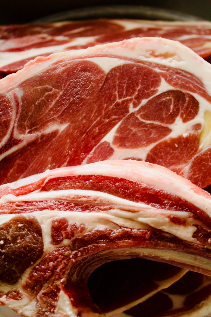 Detailed close-up of raw lamb chops highlighting intricate marbling and rich color.